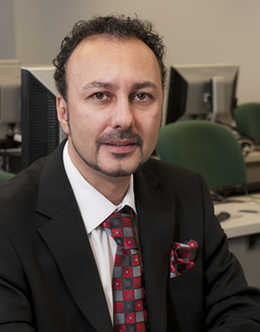 Steve Serhat Deveny at desk in front of computers