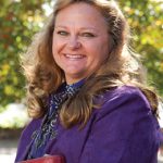 Judith Dierkes posing in purple shirt with red book