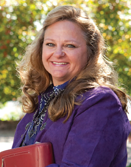 Judith Dierkes posing in purple shirt with red book