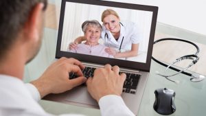 man looking at woman and nurse on laptop screen