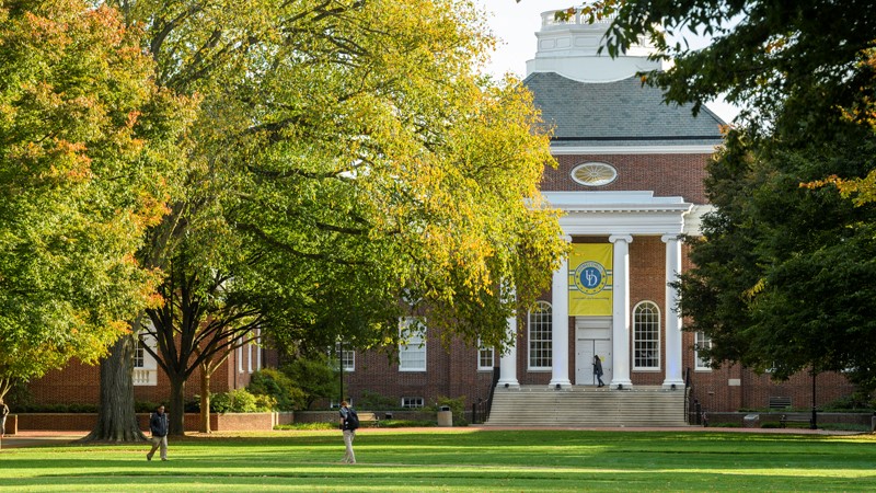 Front of Memorial Hall with steps, white columns and brick facing from The Green