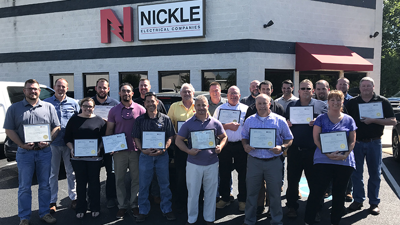 Group of Nickle employees in front of their building with certificates