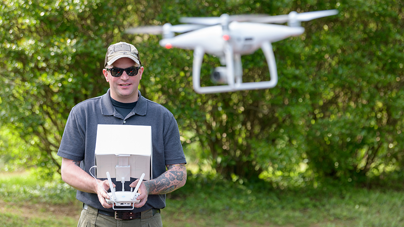 student Tavis Miller flying drone in a park