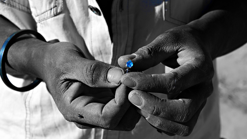 two hands of a man holding a mineral