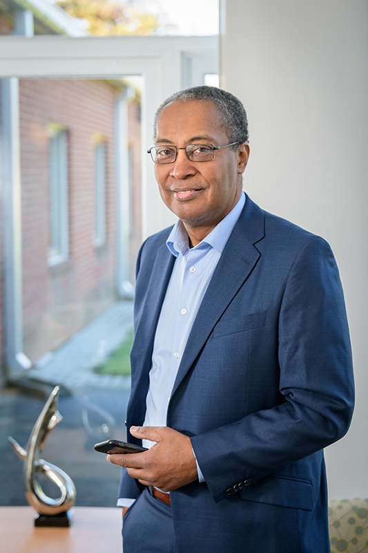 Tony Powell standing in front of window with smartphone in left hand