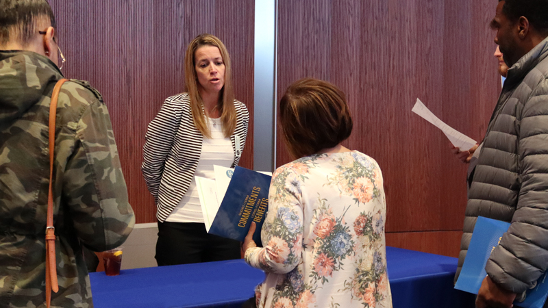 Instructor Amanda Bullough speaks with prospective students from behind table