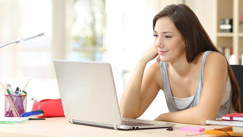 female high school student taking an online class on laptop