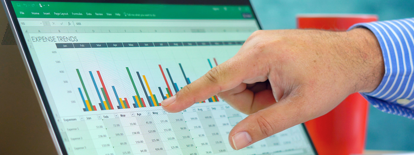 Hand pointing at Microsoft Excel bar chart on tablet