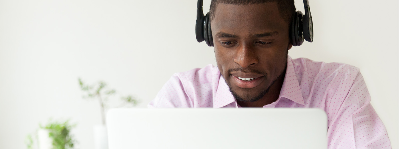 A middle-aged man with headphones working on a laptop.