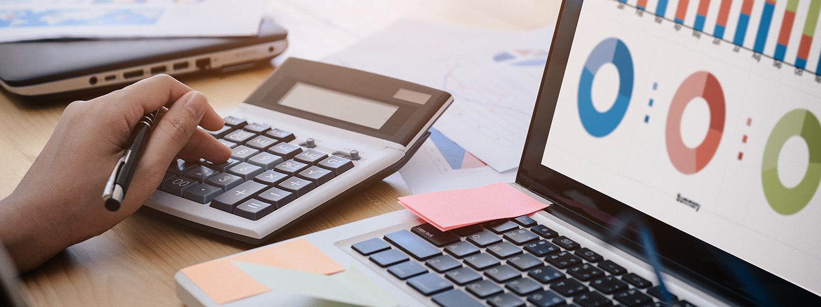 woman's left hand on calculator next to laptop