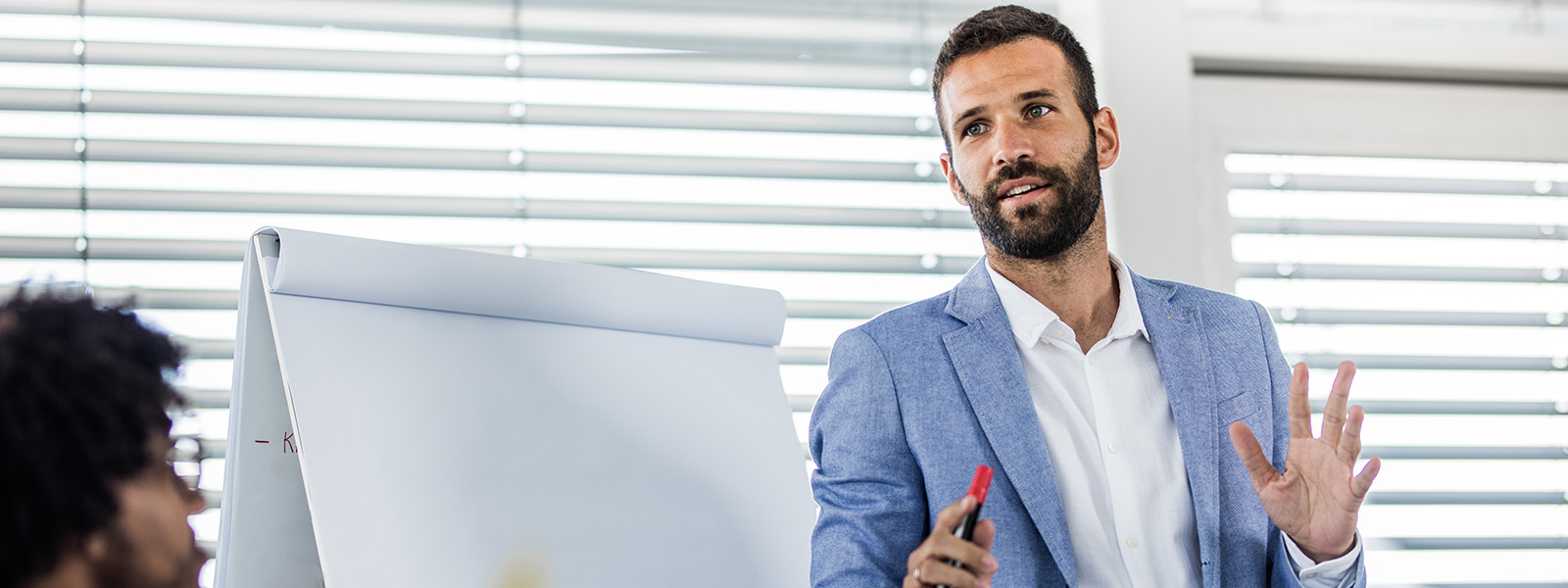 Man wearing sport coat giving presentation in front of large pad and easel