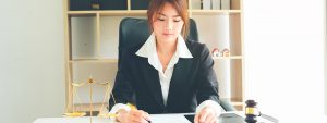 Female lawyer sitting at desk writing on pad