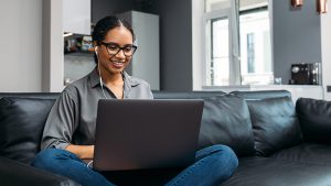 Woman at home sitting on couch working on laptop