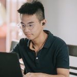 Male teenager sitting at table working on laptop