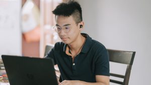 Male teenager sitting at table working on laptop