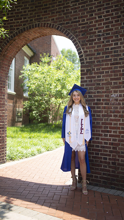 Lauren Conforti posing in cap and gown on UD campus