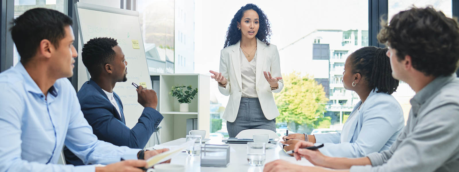 Young woman standing in front of a group of colleagues giving a presentation.