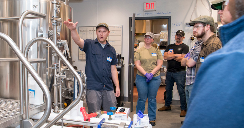 Brewing course instructor shows students professional brewing equipment.