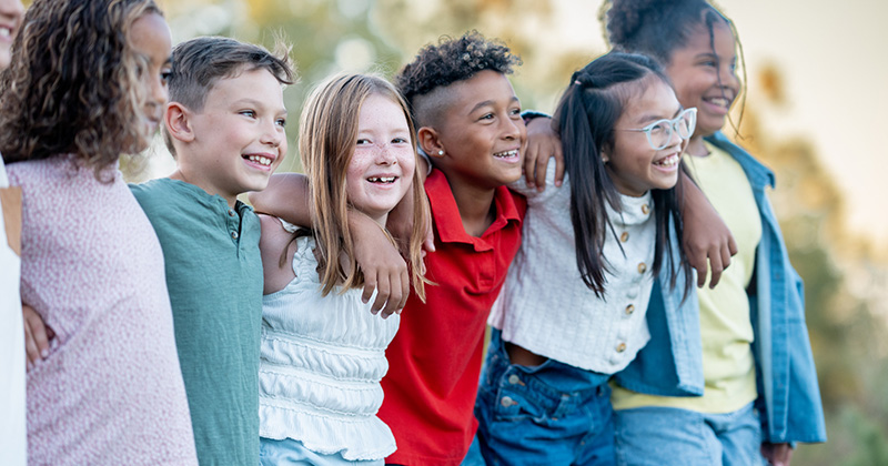 Smiling children in a line locking arms. Register button at the bottom