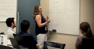 Julie Harris writing on whiteboard with team members looking on.