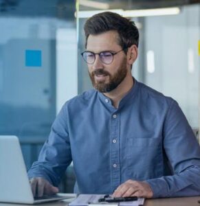 Man working on a laptop in an office setting.