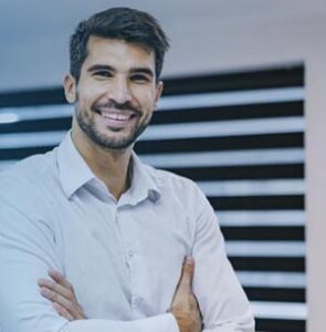 Smiling man, arms folded, in office