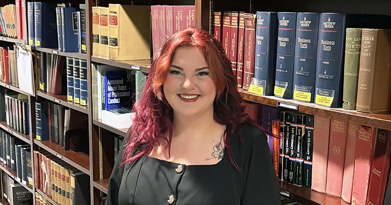 Lindsay Spiece standing in front of a bookcase filled with legal books.