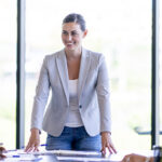 Person standing at the head of a conference table leading a meeting.