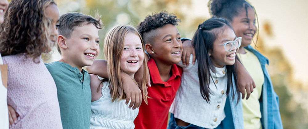Elementary-age children standing arm in arm outdoors during a school activity.